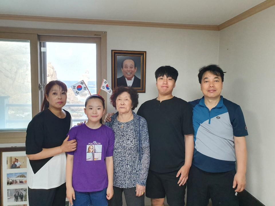 The late Kim Sin-yeol, center, the only resident of Dokdo, poses for a commemorative photo with her daughter, son-in-law, grandson and granddaughter at the residents’ quarters on Seodo in Dokdo-ri, Ulleung-eup, Ulleung County, North Gyeongsang. A photo of her late husband Kim Sung-do hangs behind her. [YONHAP] 