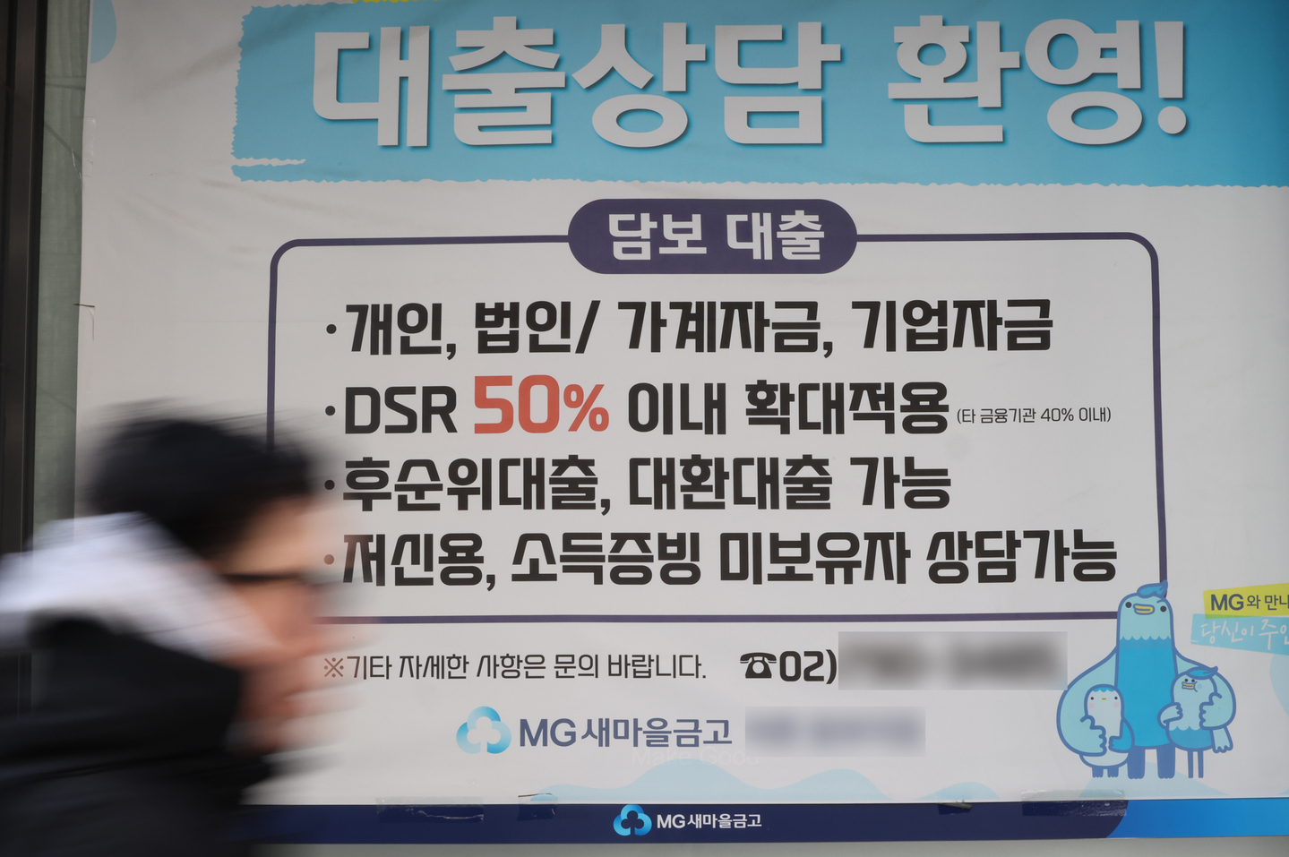 A pedestrian walks past a loan advertisement posted at a Saemaul Geumgo branch in Seoul on March 8. [YONHAP]