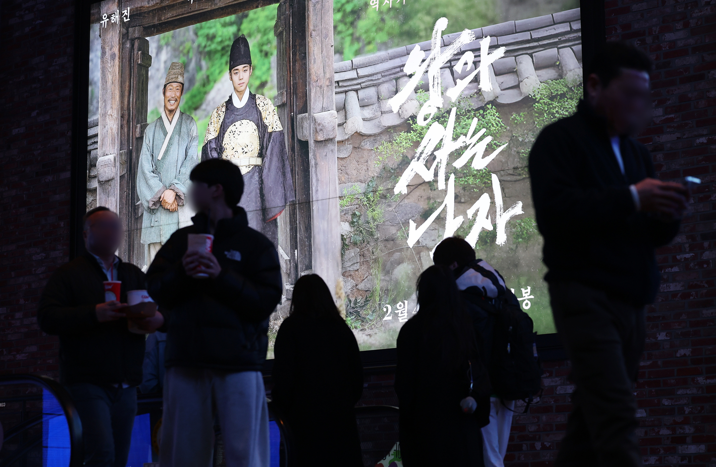Moviegoers walk past a poster of the historical drama film ″The King's Warden″ displayed on an electronic board at a theater in Yongsan District, central Seoul, on March 8. [NEWS1] 