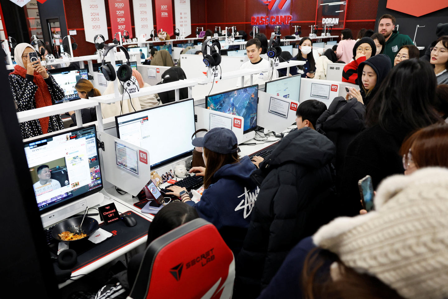 People gather around a BTS fan at an internet cafe in Seoul on Jan. 22 as the individual tries to book a ticket for BTS’s first concerts in Korea in years as part of its world tour. [REUTERS/YONHAP]