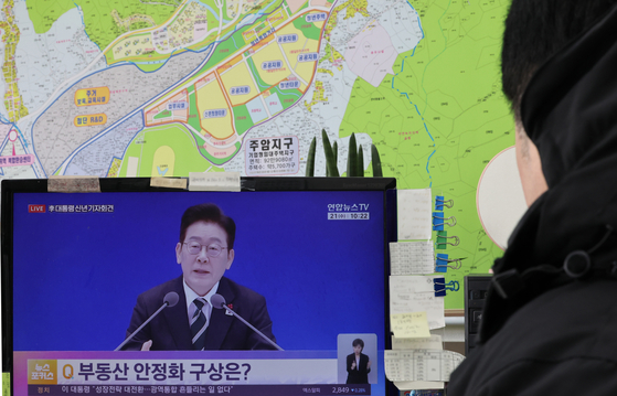 A real estate agent watches a broadcast of President Lee Jae Myung’s New Year press conference at a real estate brokerage office in Seocho District, Seoul, on Jan. 21. The government’s housing policies since the second half of 2025 have focused largely on strongly curbing demand in the property market. [YONHAP]
