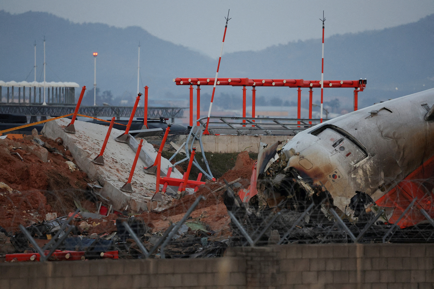 The wreckage of the Jeju Air aircraft lies near a concrete structure that it crashed into at Muan International Airport in South Jeolla on Dec. 30, 2024. [REUTERS/YONHAP] 