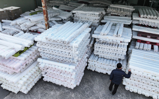 A person looks at bolts of fabric stacked outside a factory in Gyeongsan, North Gyeongsang on March 12. 