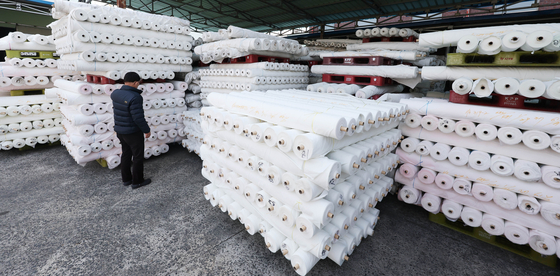 A person looks at bolts of fabric stacked outside a factory in Gyeongsan, North Gyeongsang on March 12. 