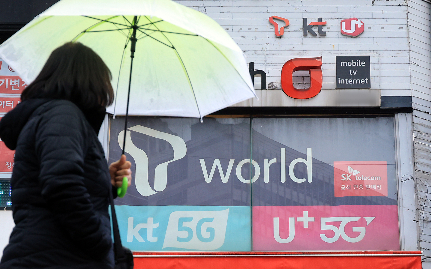 A pedestrian walks by mobile phone stores in Seoul on Dec. 23, 2024. [NEWS1]