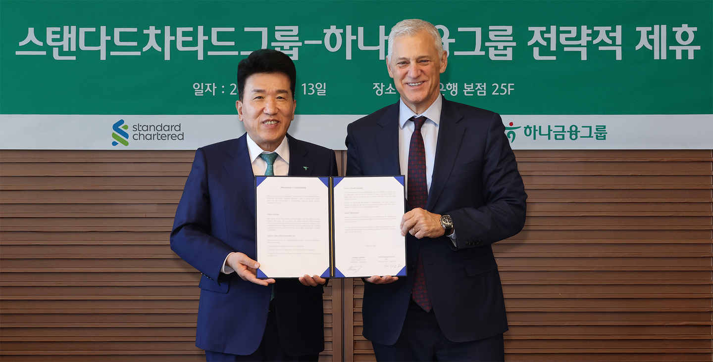 Hana Financial Group Chairman Ham Young-joo, left, and Standard Chartered Group CEO Bill Winters hold a signed agreement during an MOU ceremony on global business and digital asset cooperation at Hana Bank headquarters in Jung District, central Seoul, on March 13. [HANA FINANCIAL GROUP]