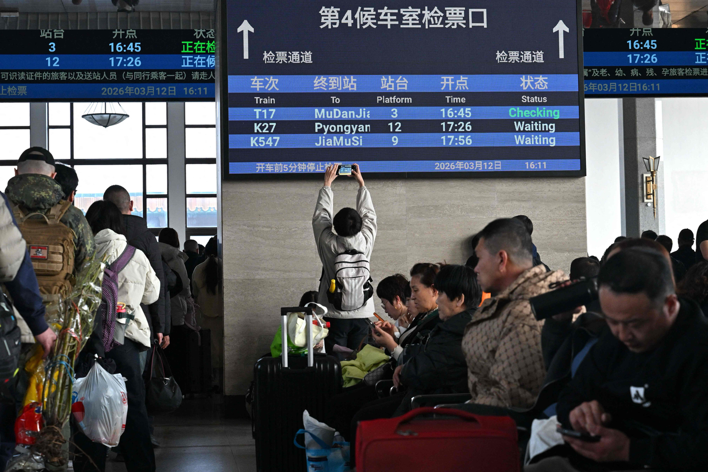 A man takes pictures of a board with a sign for the train bound for Pyongyang as passengers wait at Beijing Railway Station in Beijing on March 12. The first passenger train service from North Korea to China crossed the border March 12 for the first time in six years. [AFP/YONHAP]