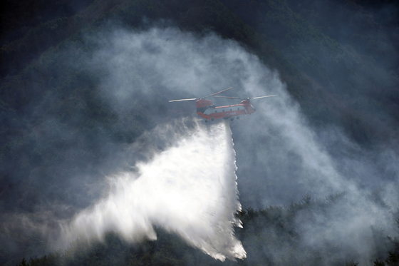 A forestry helicopter conducts wildfire suppression operations in Hamyang County, South Gyeongsang, on Feb. 23. [YONHAP]
