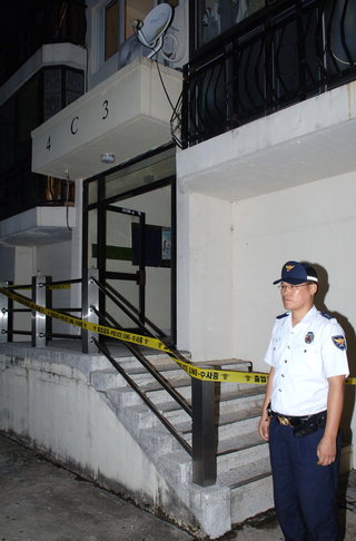A police officer stands guard at the main entrance of the apartment block in Ulsan where the arson occurred in September 2006. [SCREEN CAPTURE]