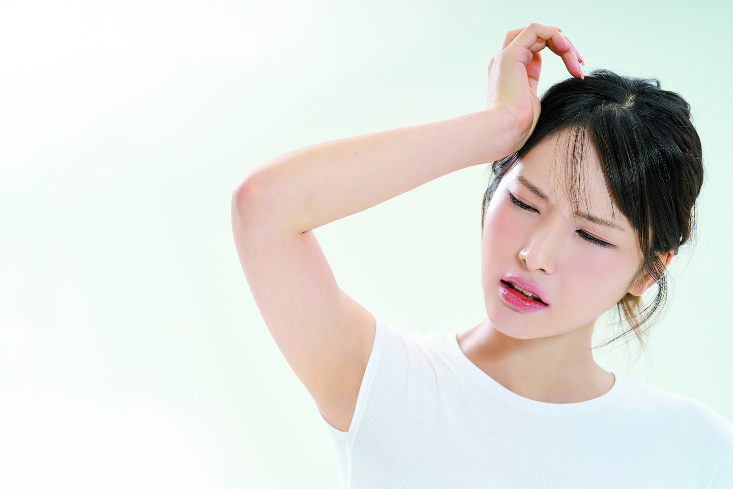 A woman is frowning and clenching her head. [GETTY IMAGE BANK]