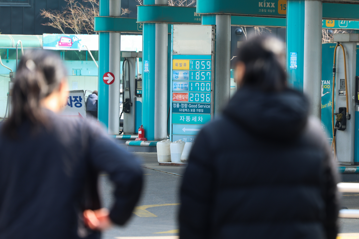 Pedestrians walk by a sign displaying fuel prices in front of a gas station in Seoul on March 17 as prices soar amid the tension in the Middle East. [YONHAP]