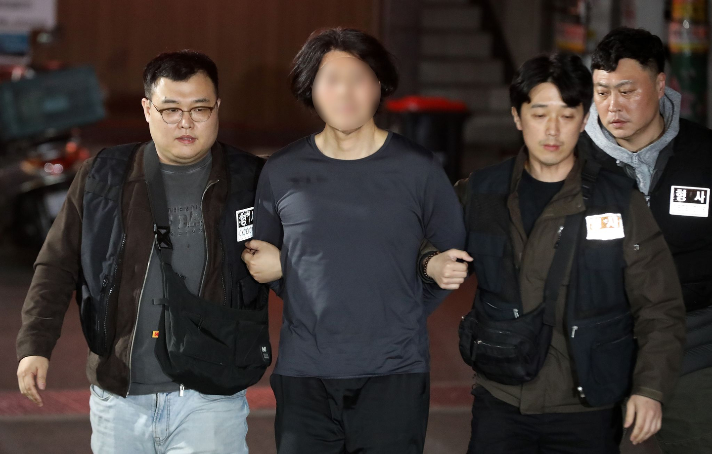A suspect accused of fatally stabbing an airline captain at an apartment building in Busan, center, is transferred to the Busan Busanjin Police Station on March 17. [NEWS1]