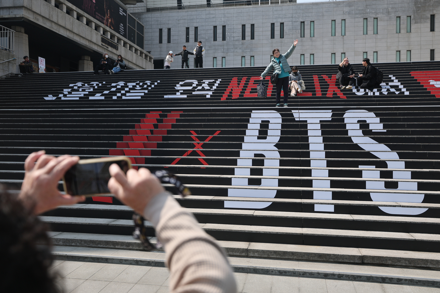 Fans pose with murals promoting the BTS comeback concert on the steps of the Sejong Center for the Performing Arts in Jongno District, central Seoul, on March 17. [YONHAP]