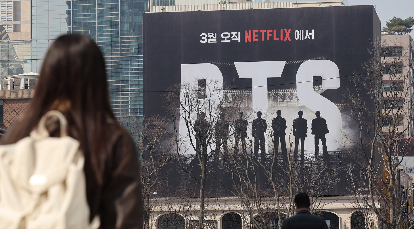 A pedestrian walks past an outdoor billboard on March 17 advertising BTS's upcoming concert in Gwanghwamun in central Seoul. [NEWS1]