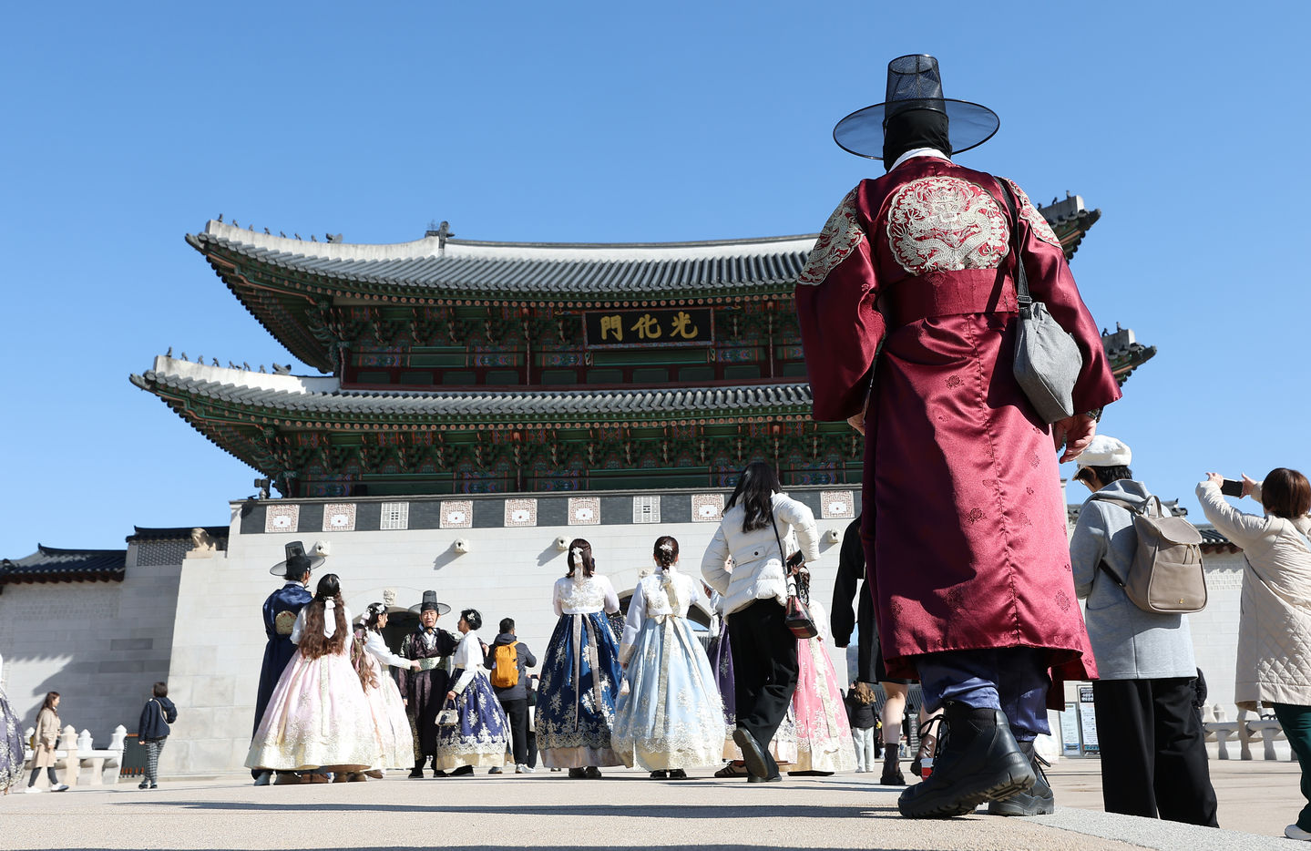 Tourists walk around Gwanghwamun wearing "hanbok" (traditional Korean dress) in central Seoul on March 19. [YONHAP]
