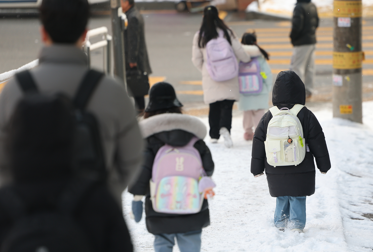 Children and their caretakers walk down a slope near an elementary school in Seodaemun District, western Seoul, on Feb. 2. [YONHAP]