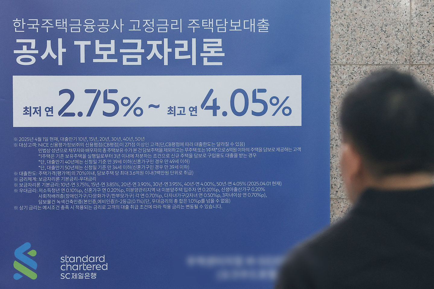 A passerby walks past a poster promoting home mortgage loans put up at a bank in central Seoul on Dec. 7, 2025. [YONHAP]