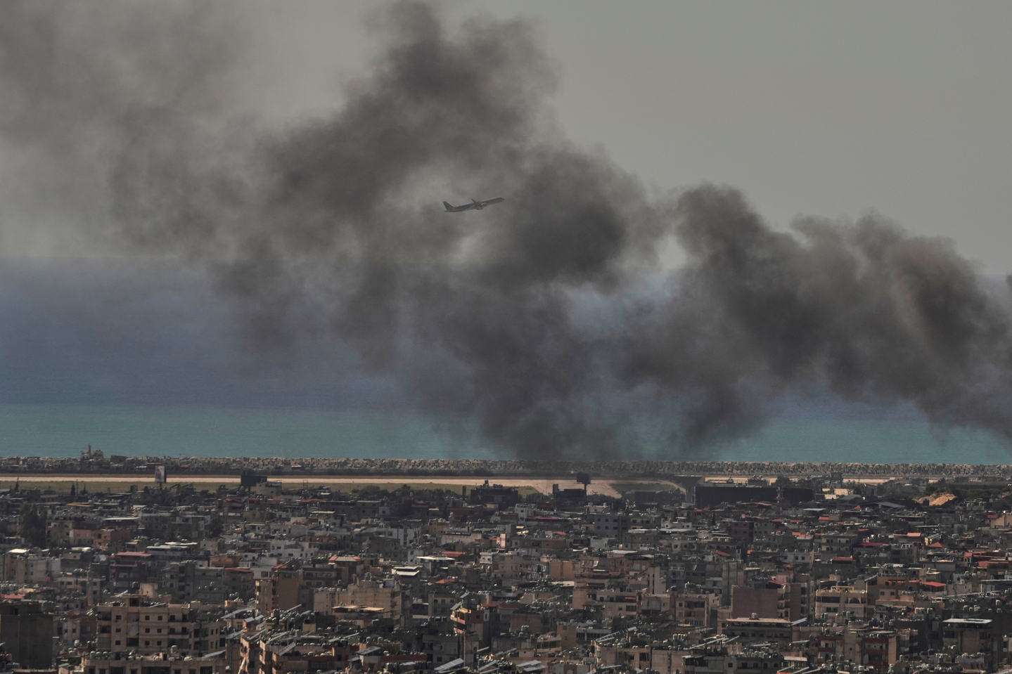 A Middle East Airlines plane takes off from Rafik Hariri International Airport as smoke rises from the site of an Israeli airstrike in Dahiyeh, Beirut's southern suburbs, Lebanon, on March 17. [AP/YONHAP] 