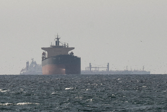 Cargo ships float near the Strait of Hormuz, as seen from northern Ras al-Khaimah, near the border with Oman’s Musandam governance, amid the U.S.-Israeli conflict with Iran, in United Arab Emirates, March 11. [REUTERS/YONHAP]