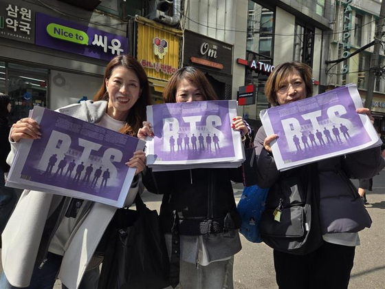  Fans pose with the BTS special edition of the Korea JoongAng Daily in central Seoul on March 21. [KIM MIN-YOUNG]
