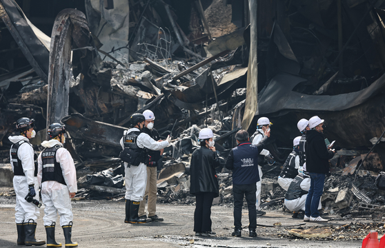 Police and fire personnel inspect the site of a blaze at an auto parts factory in Daejeon on March 22. The fire, which broke out on Friday, resulted in 14 deaths. [NEWS1]