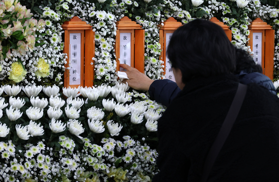 A bereaved family member touches her son’s name at a joint memorial altar for victims of the fire at Anjun Industrial in Daejeon Metropolitan City Hall on March 22. [YONHAP]