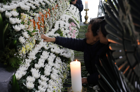 A bereaved family member touches her son’s name at a joint memorial altar for victims of the fire at Anjun Industrial in Daejeon Metropolitan City Hall on March 22. [YONHAP]
