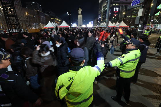 Police officers guide a massive flock of concertgoers out of Gwanghwamun Square in central Seoul following boy band BTS's comeback performance on March 21. [YONHAP]