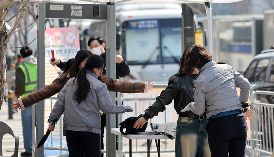Passersby undergo security checks after passing through walk-through metal detectors near Gwanghwamun Square in Jongno District, central Seoul, ahead of BTS's comeback performance on March 21. [NEWS1] 