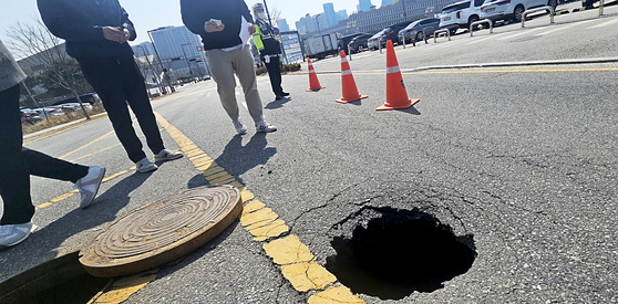 A sinkhole is seen on a road near the government complex in Eojin-dong, Sejong, on March 23. Police controlled the road while Sejong officials discussed response measures. [NEWS1]