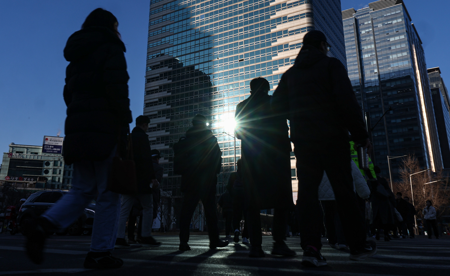 Pedestrians walk across a crosswalk at an intersection near Gwanghwamun Square in Jongno District, central Seoul, on Feb. 19. [NEWS1]