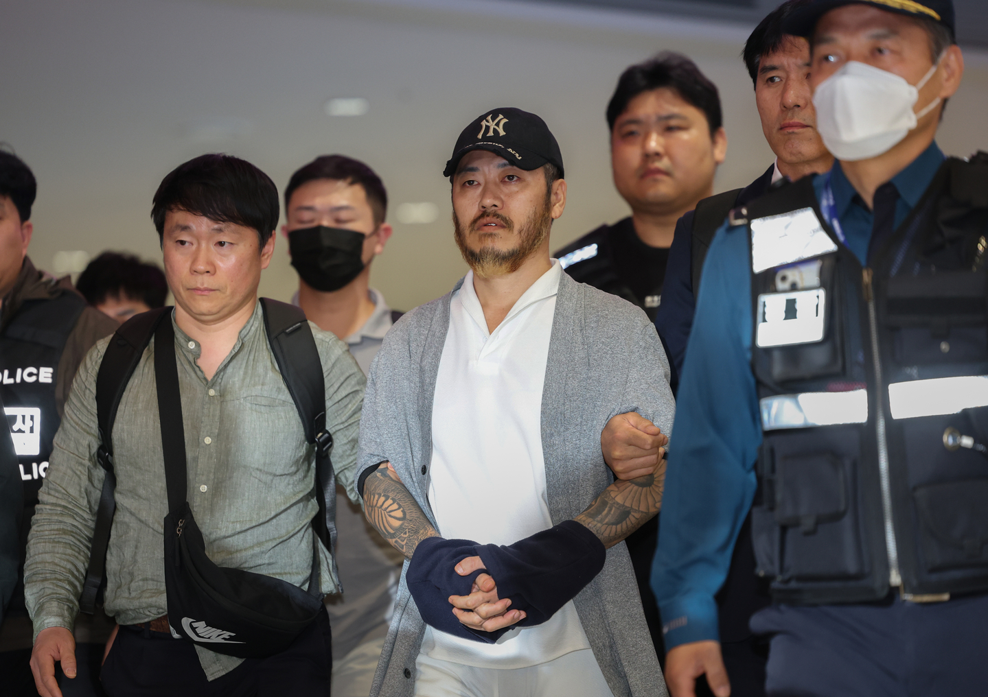 Park Wang-yeol, center, a convicted criminal accused of smuggling drugs into Korea, is escorted by police officials at Incheon International Airport on March 25. [YONHAP]
