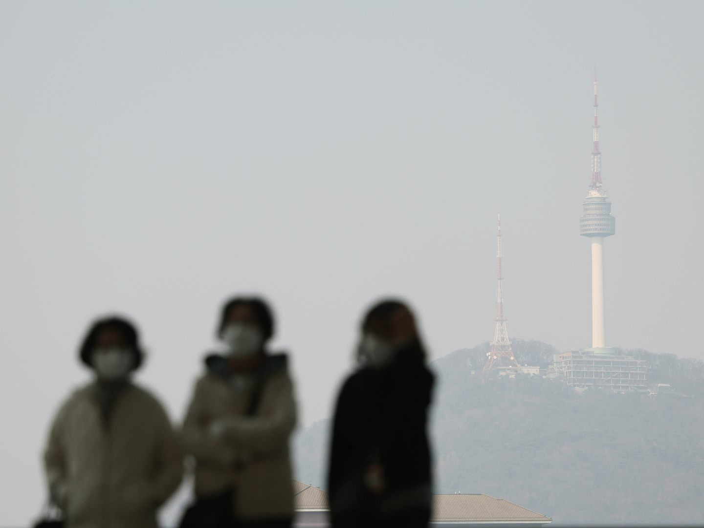 Pedestrians walk in masks in the streets of Seoul amid a fine dust warning on March 17. [NEWS1]
