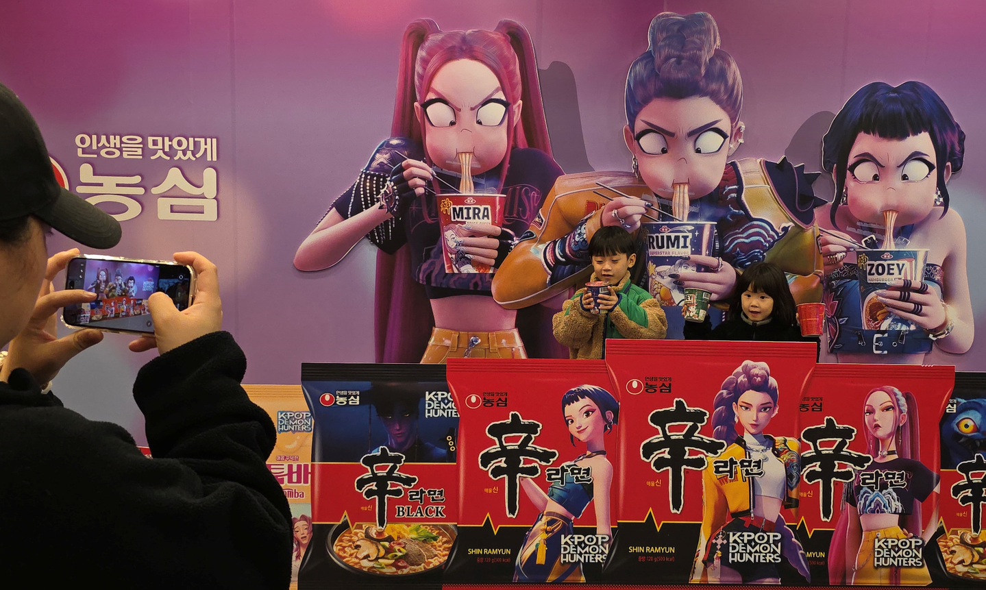 Visitors take photos in front of a display featuring characters eating ramyeon from the Netflix animated film “KPop Demon Hunters” at a festival in Gumi, North Gyeongsang, on Nov. 7, 2025. [NEWS1] 
