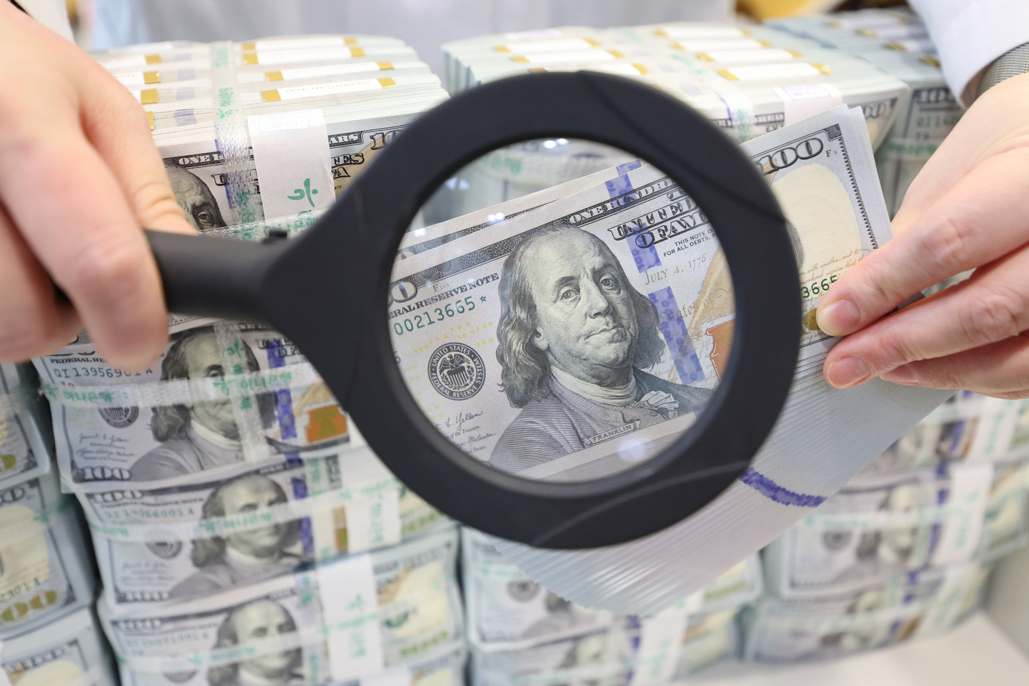 An employee at Hana Bank's counterfeit response center in central Seoul examines dollars bills. [YONHAP]