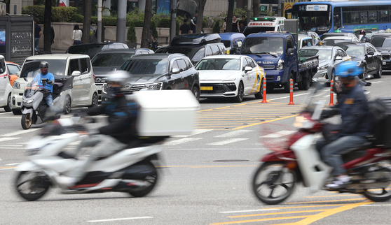 Delivery workers drive past a street in Gangnam District, southern Seoul, on June 17, 2025. [YONHAP]