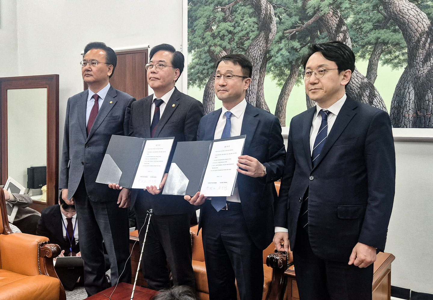 Democratic Party floor leader Han Byung-do, second from right, and People Power Party floor leader Song Eon-seog, second from left, hold up copies of their agreement on the schedule for April's extraordinary session of the National Assembly, flanked by their respective deputies, at the Assembly building in Yeouido, western Seoul, on March 30. [YONHAP]