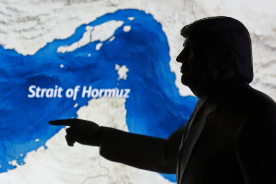 A map showing the Strait of Hormuz and a 3D printed miniature model depicting U.S. President Donald Trump are seen in this illustration taken March 23, 2026. [REUTERS/YONHAP]