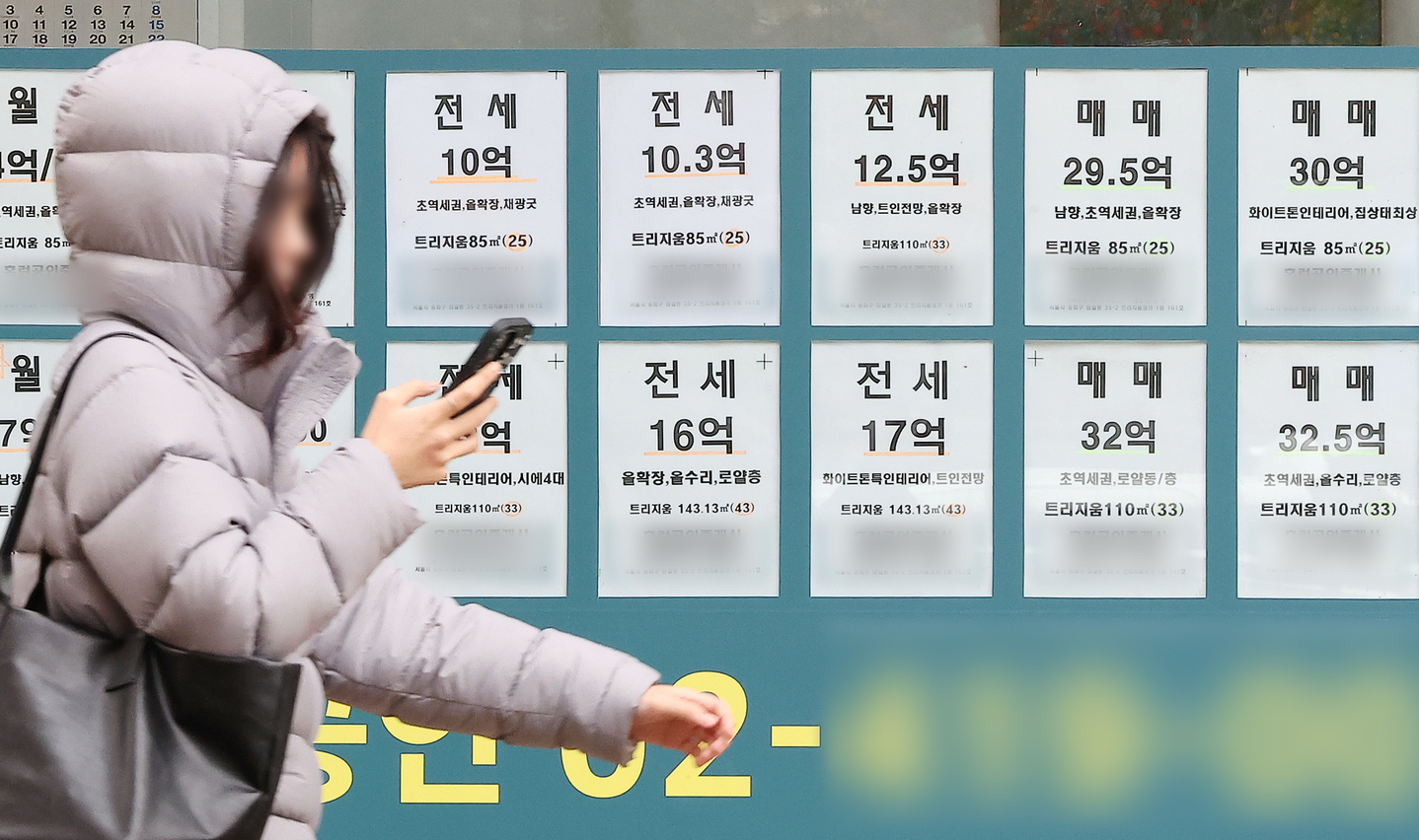 A pedestrian passes by a real estate agency with listings for nearby apartments in Seoul on Nov. 24, 2025. [NEWS1]