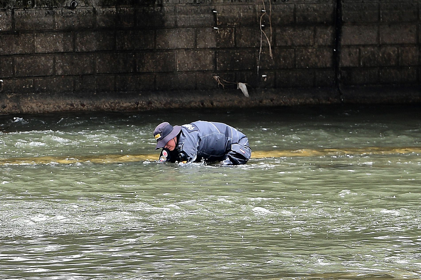 A police official looks for a suitcase that was thrown into a stream near Chilseong-dong, Daegu, after a report was filed about a suspicious suitcase floating in the stream on March 31. A body was found inside the suitcase after police retrieved it. [NEWS1]