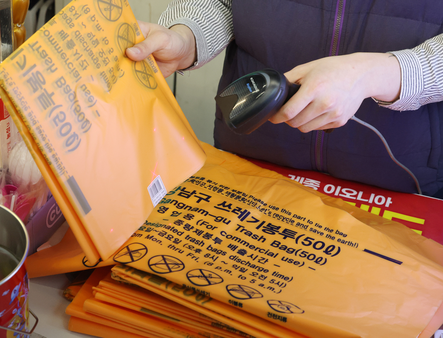 An employee rings up a bundle of garbage bags at a convenience store in Gangnam District, southern Seoul, on March 24. [NEWS1]