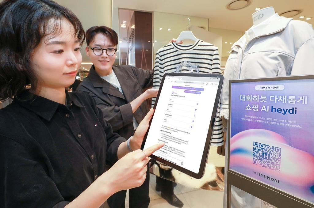 A Hyundai Department Store employee uses a generative AI shopping assistant called “Heydi” to offer personalized offline shopping recommendations to customers. [YONHAP]