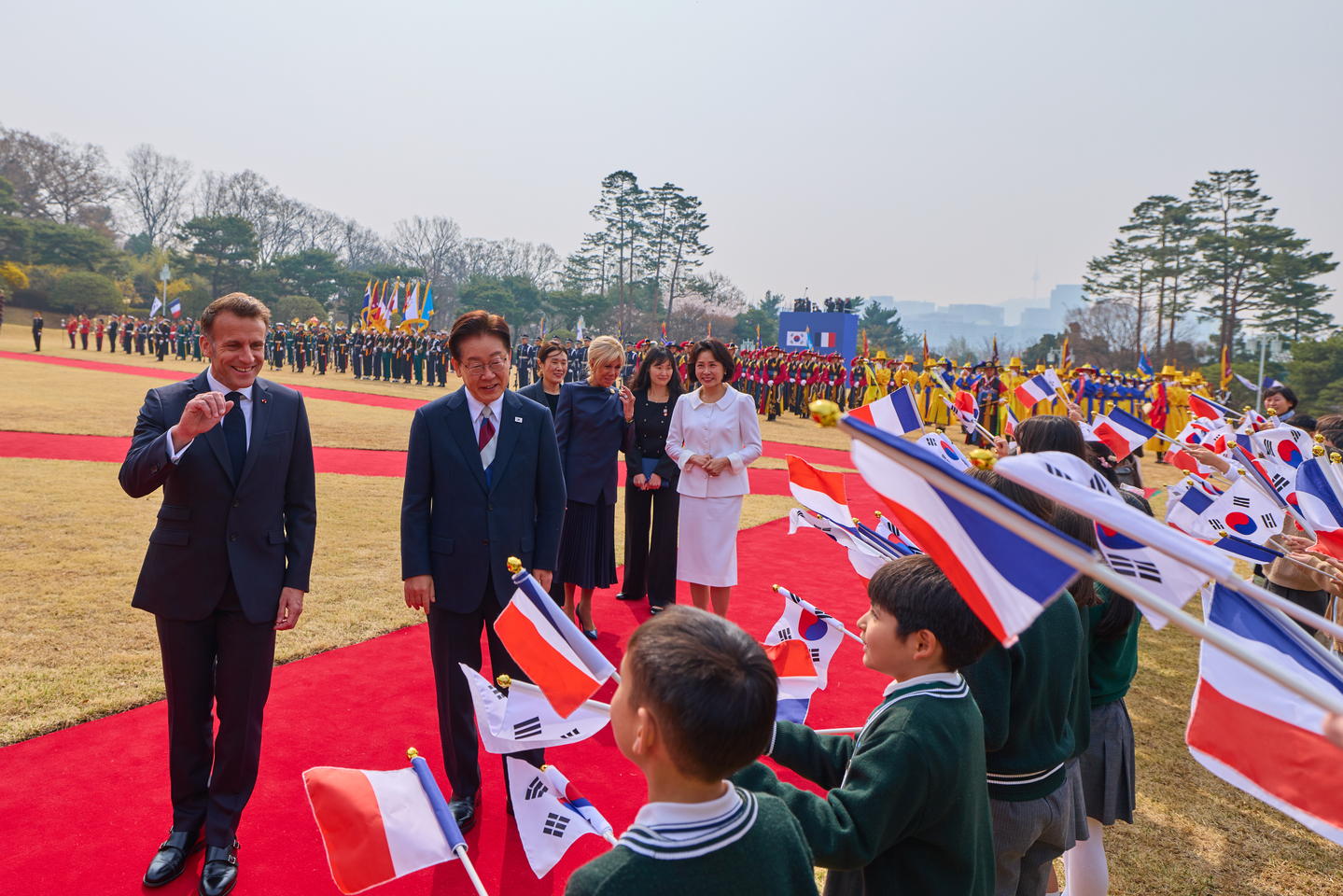 President Lee Jae Myung, right, and French President Emmanuel Macron, left, greet children during the welcome ceremony ahead of their bilateral summit at the Blue House in Seoul on April 3. [JOINT PRESS CORPS]