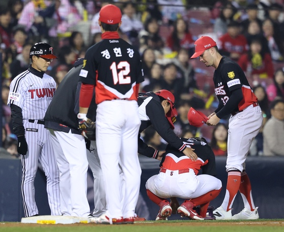 Kia Tigers third baseman Kim Do-yeong, second from right, stays crouched in pain after a diving catch attempt during a KBO regular-season game against the LG Twins at Jamsil Baseball Stadium in southern Seoul on April 1. [YONHAP]