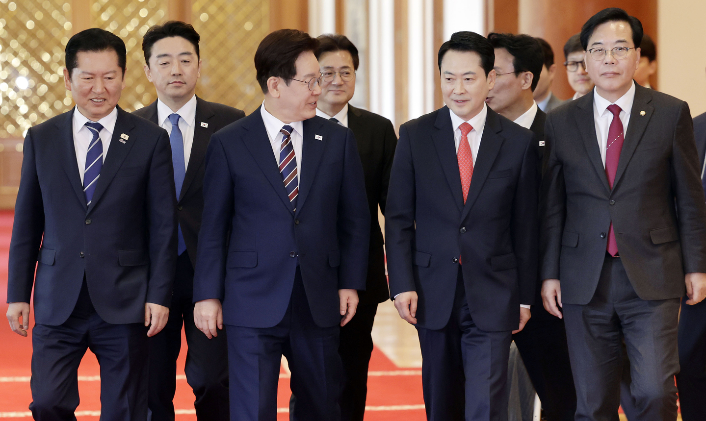 President Lee Jae Myung, second from left in the front row, walks with Democratic Party Chairman Jung Chung-rae, People Power Party Chairman Jang Dong-hyeok and presidential aides to a luncheon meeting at the Blue House in central Seoul on April 7. [JOINT PRESS CORPS]
