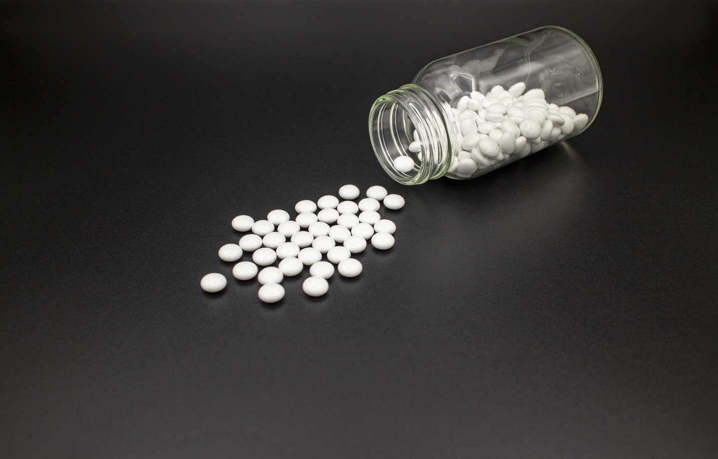 White tablets spill from a glass bottle [GETTY IMAGES]