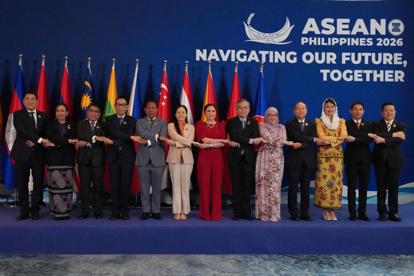 Leaders link arms during a group photo at the 32nd Asean Economic Ministers' Retreat in Manila on March 13. [AFP/YONHAP]