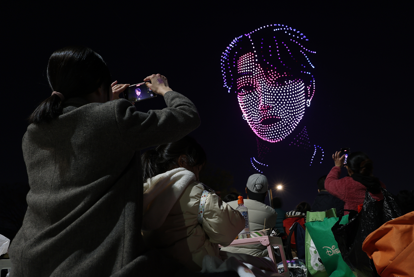 Audience member takes a photo during ″KPop Demon Hunters Hangang Drone Show Encore” in Yeouido Hangang Park in Yeongdeungpo District, western Seoul, on Nov. 15, 2025. [YONHAP]