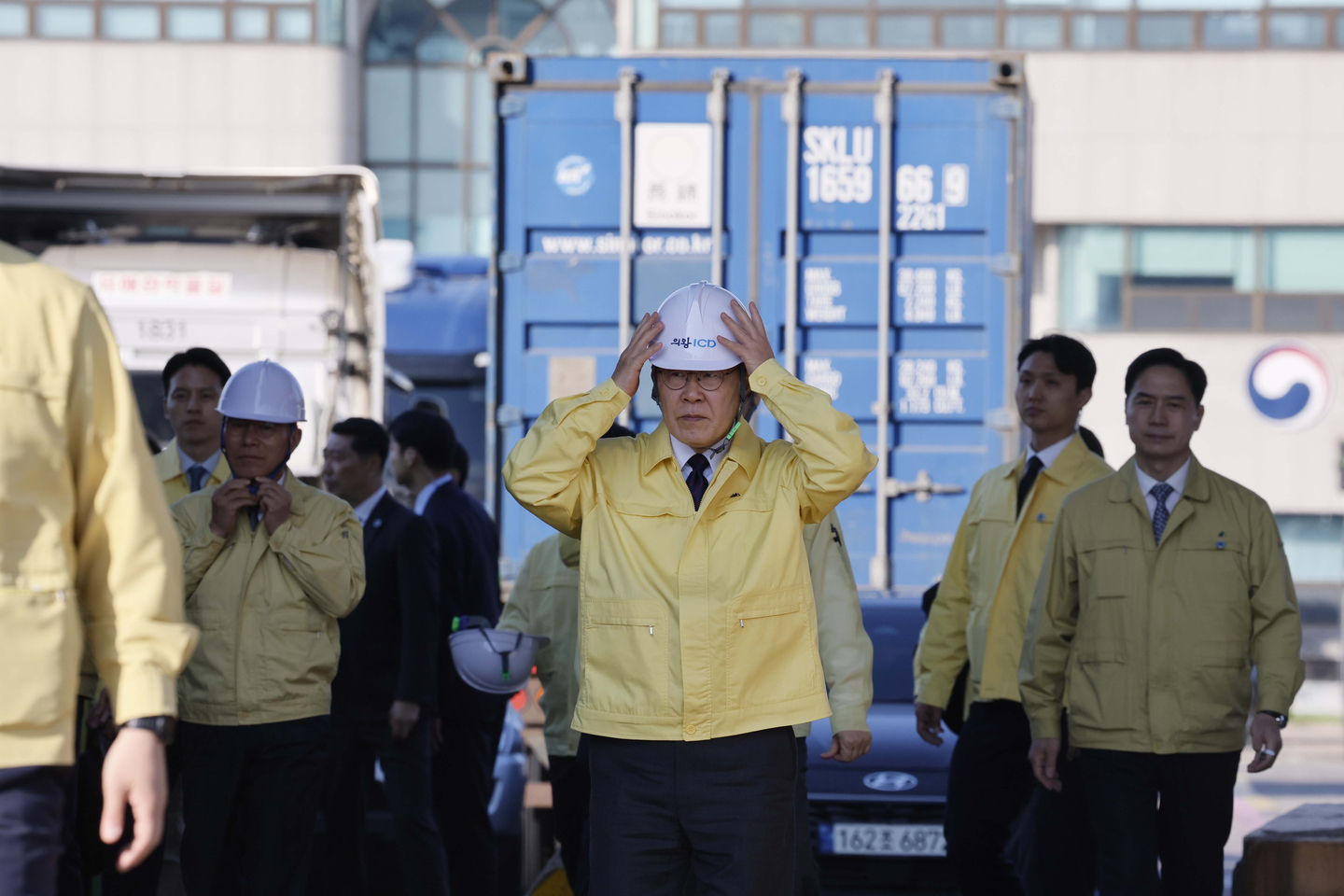 President Lee Jae Myung, center, adjusts his safety helmet as he inspects the Uiwang Inland Container Depot, a logistics hub in Gyeonggi, on April 8. He later spoke with stakeholders in the shipping and logistic industries to discuss how to deal with high oil prices due to the Middle East crisis after the United States and Iran agreed to a two-week ceasefire agreement. [JOINT PRESS CORPS]