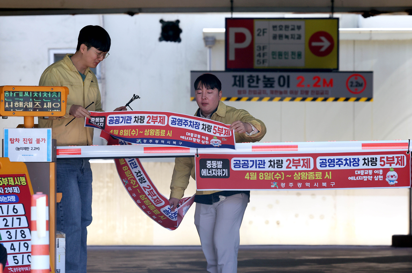 Public servants attach a banner notifying users of the two-day rotation driving and parking system at a parking space at Buk District Office in Gwangju on April 7. [BUK DISTRICT] 